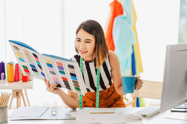 Young Asian designer woman choosing multicolor chart and holding coffee cup at workplace, small business startup, Business owner entrepreneur, modern freelance job lifestyle concept. asean people - Foto, afbeelding