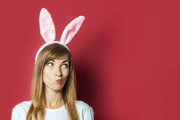 Young beautiful woman with rabbit ears on a pink background. Easter concept - Photo, Image
