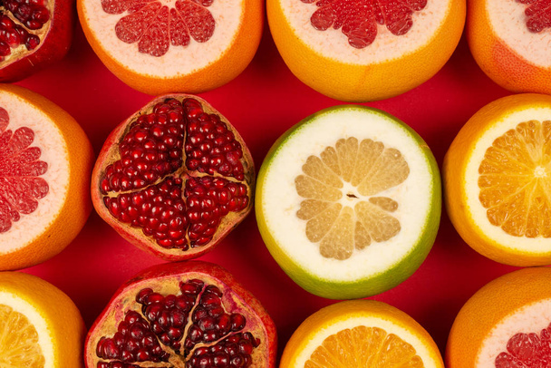 Grapefruit, orange, pomegranate, citrus sweetie on red backgroun - 写真・画像