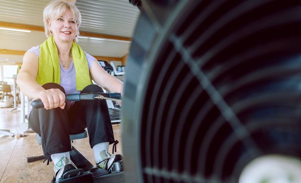 Mujer mayor en la máquina de remo en un gimnasio
 - Foto, Imagen