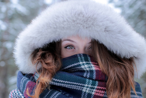 Piękna dziewczyna z zielonymi oczami i rudymi włosami w czerwonym kapeluszu na spacerze w zimowym śnieżnym lesie - Zdjęcie, obraz