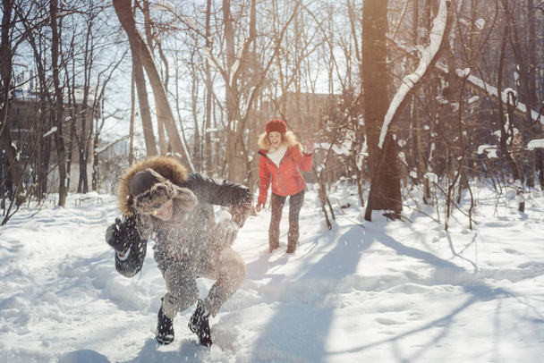 Woman throwing snowball on her guy in winter in playful mood - Photo, Image