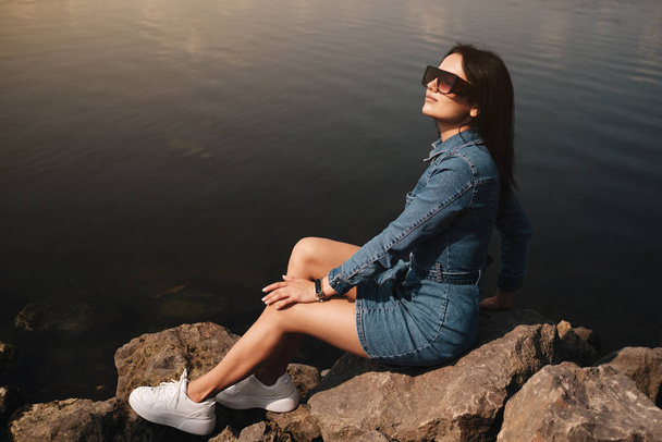 Portret van een mooi Brunette meisje gekleed in jeans jeans Overalls brengt vrije tijd - Foto, afbeelding