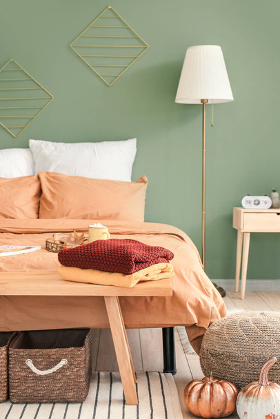 Большая удобная кровать в стильном интерьере комнаты с осенним декором
 - Фото, изображение