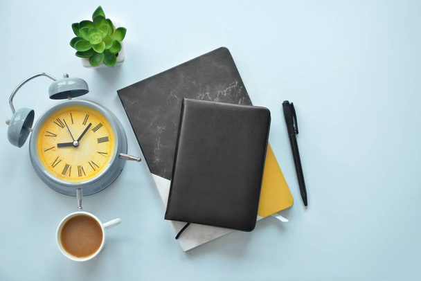 Stylish notebooks with alarm clock and cup of coffee on white table - Foto, afbeelding