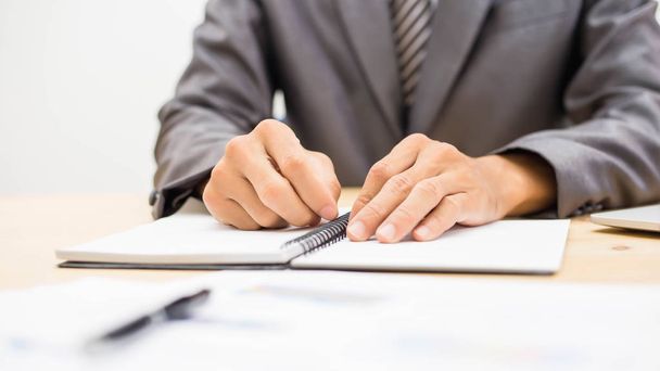 Χαρούμενος επιχειρηματίας κρατά σημειώσεις ενώ εργάζεται στο γραφείο. - Φωτογραφία, εικόνα