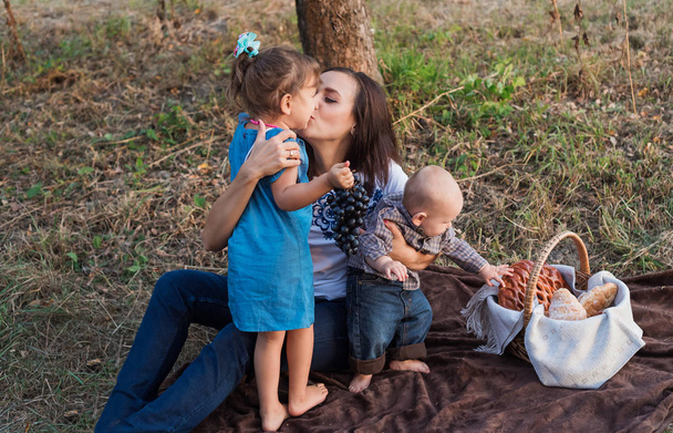 Мама нежно целует свою маленькую дочь в щеку. Семейный пикник
 - Фото, изображение