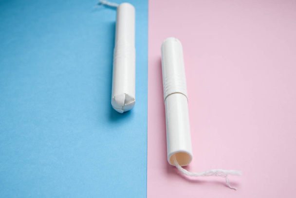 Hygienische Tampons auf blauem und rosa Hintergrund. Kopierraum, Menstruations-Hygiene-Tampon zum Schutz der Frau. Kritische Tage. Medizinische Konzeption - Foto, Bild