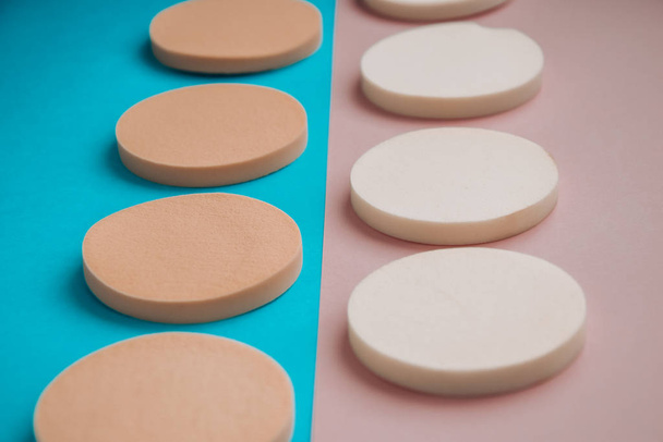White and beige makeup cosmetic foundation sponges on the blue and pink background, Close up - Fotoğraf, Görsel