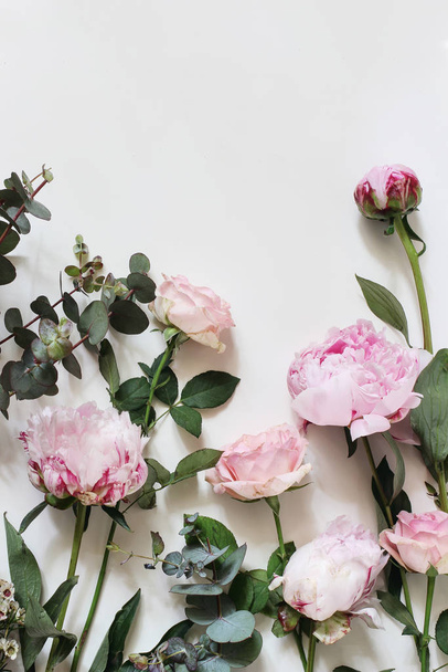Kobiecy styl Fotografia Stockowa z różowymi różami, piwonia, kwiaty i eukaliptusa liści i gałęzi izolowanych na białym tle. Płaskie łóżko, widok z góry. Wzór kwiatowy, kompozycja narożnika, pionowy. - Zdjęcie, obraz