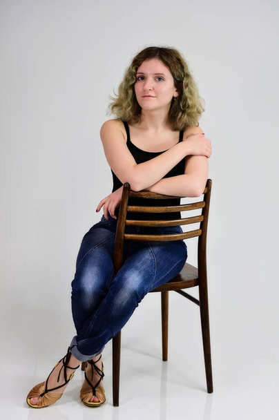 A young woman sits on a chair - Фото, изображение