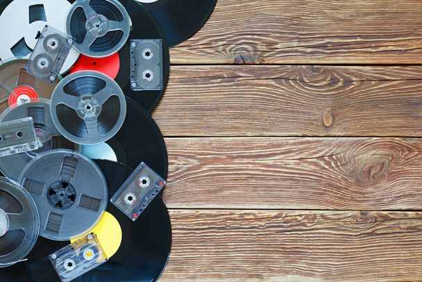 Viejas bobinas vintage, discos de vinilo y cintas de cassette sobre un fondo de mesa de madera. Etiquetas multicolores. Vista superior. Lugar para copiar espacio
. - Foto, imagen