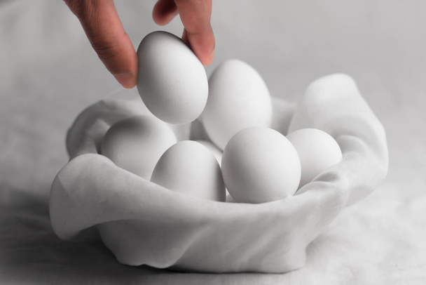 hand picking up an egg from bowl - Valokuva, kuva