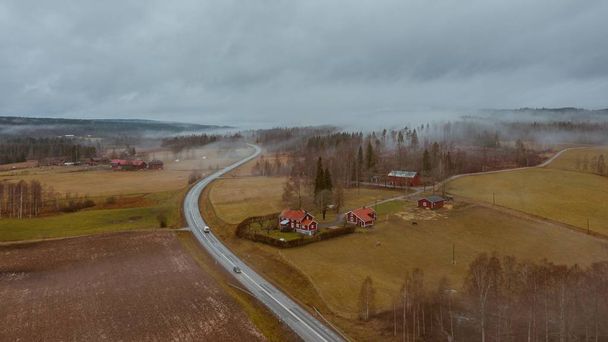 High angle shot of a road surrounded by a field with a frozen lake in the middle in Sweden - Photo, image