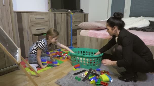 Mère fatiguée ranger les jouets et enseigne à la petite fille nettoyer dans la salle de jeux
 - Séquence, vidéo