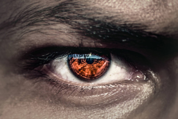 dunkle böse Augen mit orangefarbener Pupille - Foto, Bild