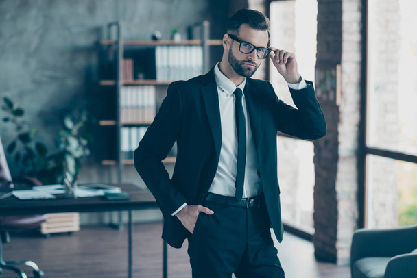 Photo of successful hot handsome business guy self-confident person teacher company trainer wear specs black blazer shirt tie pants belt suit costume standing office indoors - Фото, зображення