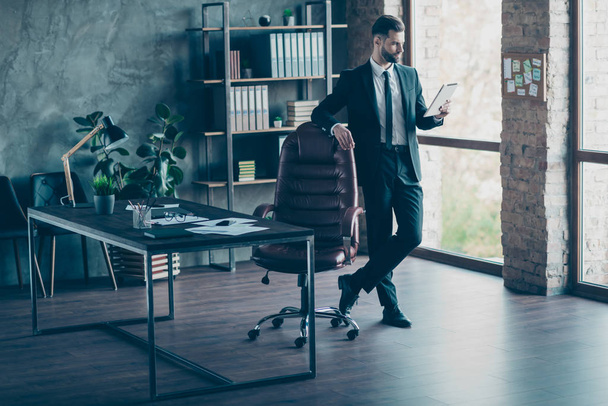 Full size photo of handsome successful business guy waiting corporate meeting read e-reader reports wear black blazer shirt tie pants suit standing modern office indoors - Photo, Image