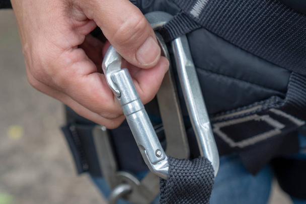 Metal carabiner in the hands of a man close-up. The concept of reliability and protection - Valokuva, kuva