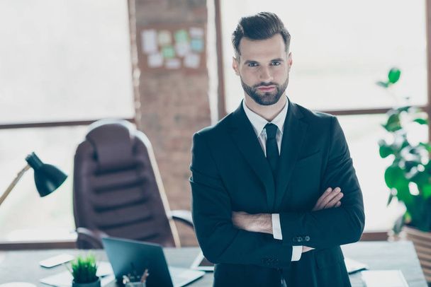 Photo of successful handsome business guy self-confident person hands crossed seriously look colleagues meeting wear black blazer shirt tie suit standing near table office indoors - Foto, Imagen