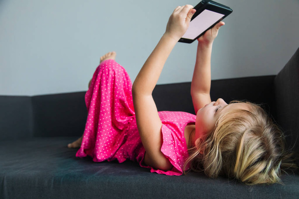 little girl reading e-book relaxed at home - Foto, Imagem