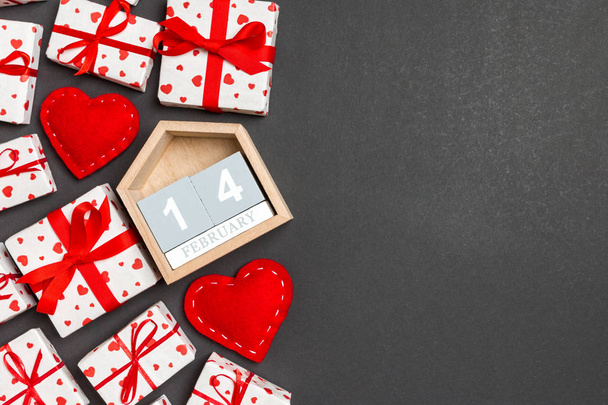 Holiday composition of gift boxes, wooden calendar and red textile hearts on colorful background with empty space for your design. The fourteenth of February. Top view of Valentine's Day concept - Photo, Image