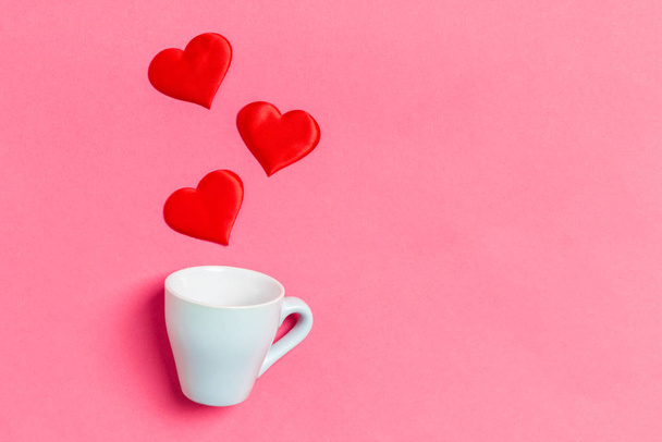 Holiday composition of red hearts falling out from a cup on colorful background. Top view of Saint Valentine's Day concept with copy space - 写真・画像