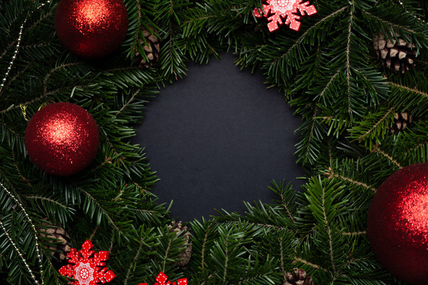 Dekoratif kar taneleri ve oyuncaklarla süslenmiş Noel çelengi. Siyah arka planda metin için yer var. Boşluğu kopyala - Fotoğraf, Görsel