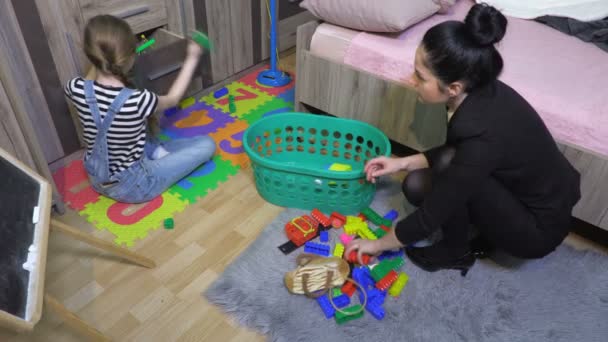  Mama sprzątać dziecko rozrzucone zabawki w brudny pokój - Materiał filmowy, wideo