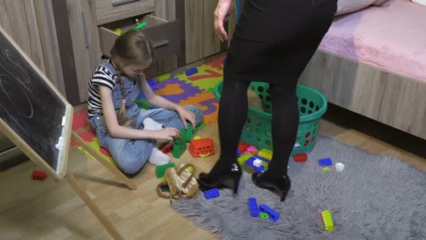  女は娘が乱雑な部屋でおもちゃを収集するのを助ける。散在するおもちゃと障害 - 映像、動画