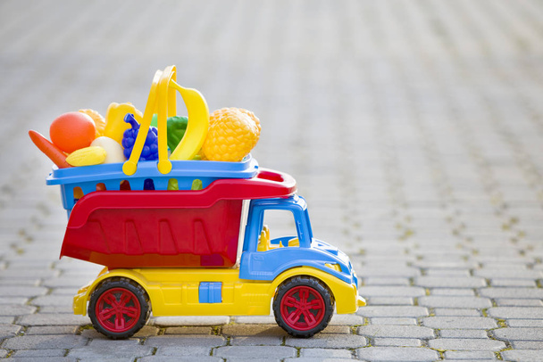 Jasny plastik kolorowy zabawka samochód ciężarowy przewożący kosz z zabawką f - Zdjęcie, obraz