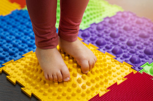 feet correction and massage - child walking on orthopedic massage puzzle floor mat - Foto, imagen