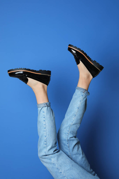 Woman wearing stylish shoes on blue background, closeup - 写真・画像