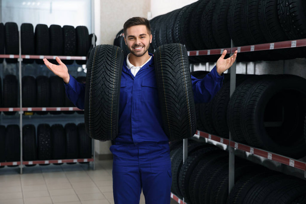 Male mechanic with car tires in auto store - Foto, Bild