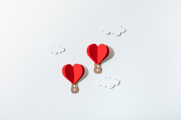 top view of paper heart shaped air balloons in clouds on white background - Foto, Imagen