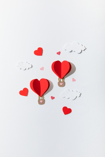 top view of paper heart shaped air balloons in clouds on white background - Фото, изображение
