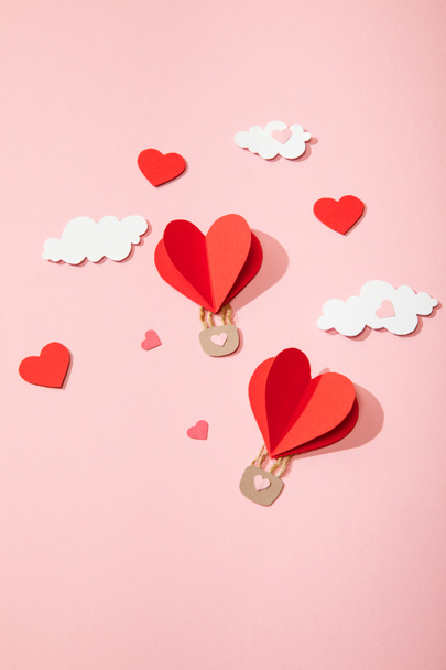 top view of paper heart shaped air balloons in clouds on pink - Foto, Bild