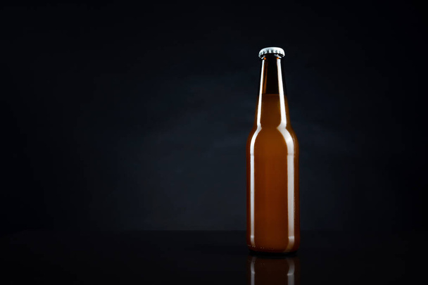 Siyah kapaklı soğuk açılmamış bira şişesi. Bir bardak buzlu buğday ya da koyu arkaplanda bira. - Fotoğraf, Görsel