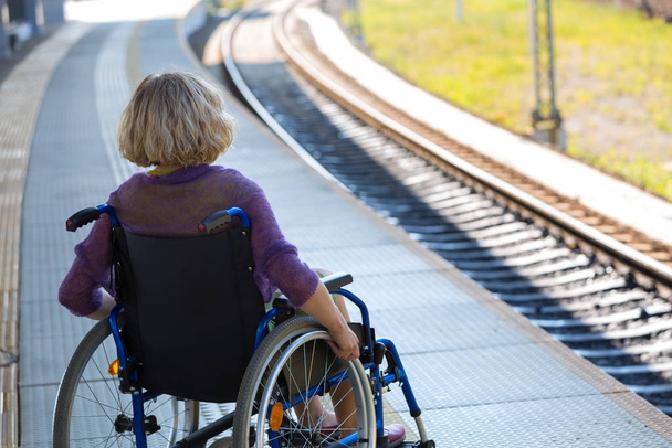 woman sitting on wheelchair on a platform - Fotó, kép