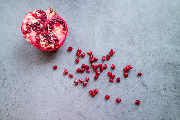 Pomegranate and its seeds on concrete backgroun. - Φωτογραφία, εικόνα