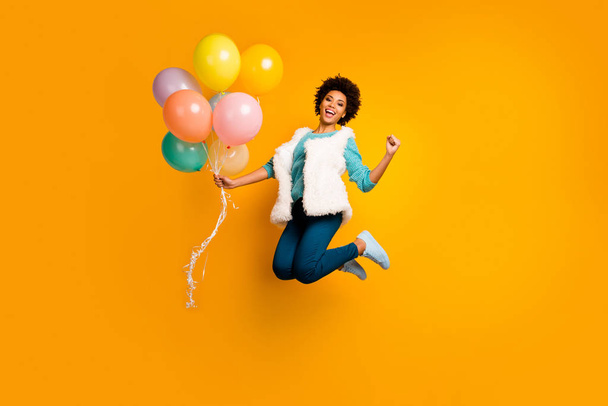 Full length photo funky crazy afro american girl jump hold balons win event scream yes raise fists wear white teal stylish trendy sweater blue pants trousers isolated bright color background - 写真・画像