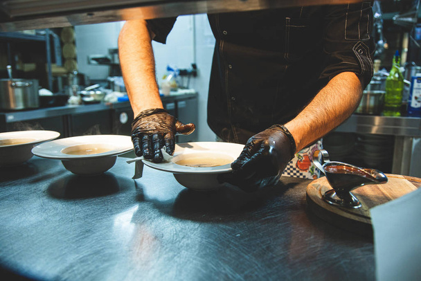The chef in the restaurant prepares dishes for serving at the counter. Close-up of gloved hands - Fotoğraf, Görsel