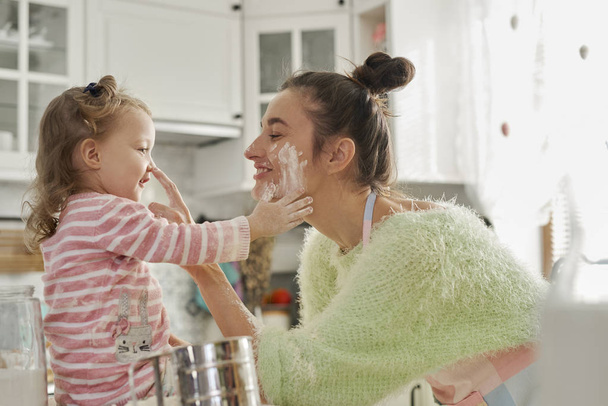 Mutter und Tochter haben Spaß mit Mehl in der Küche - Foto, Bild