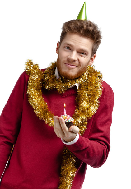 Playful man with tinsel holds small tart - 写真・画像