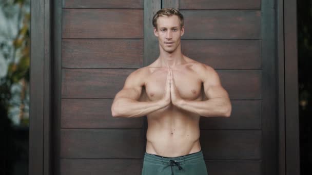 Hemdloser Mann mit muskulösem Körper macht Yoga-Übungen, meditiert, zeigt Ok-Zeichen - Filmmaterial, Video