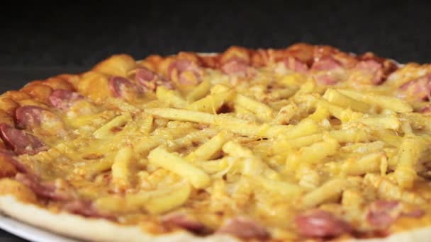 lähikuva pizzasta, jossa on juustomakkaraa, makkaraa ja kananmunaa ja joka pyörii mustalla taustalla ylhäältä
 - Materiaali, video