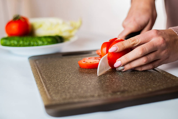 cropped shot of woman chopping fresh ripe tomato for healthy salad    - 写真・画像