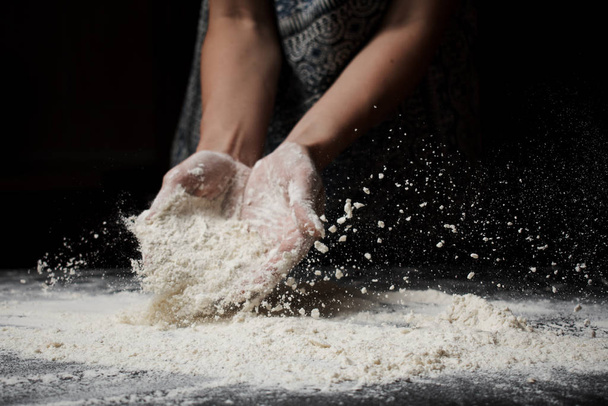 cropped shot of female hands in white flour on black background  - Foto, Imagem
