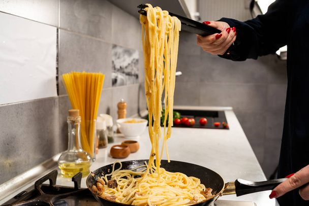 cropped shot of person cooking delicious italian pasta in kitchen - Fotoğraf, Görsel
