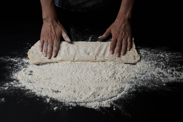 cropped shot on woman kneading dough on black background - Foto, imagen